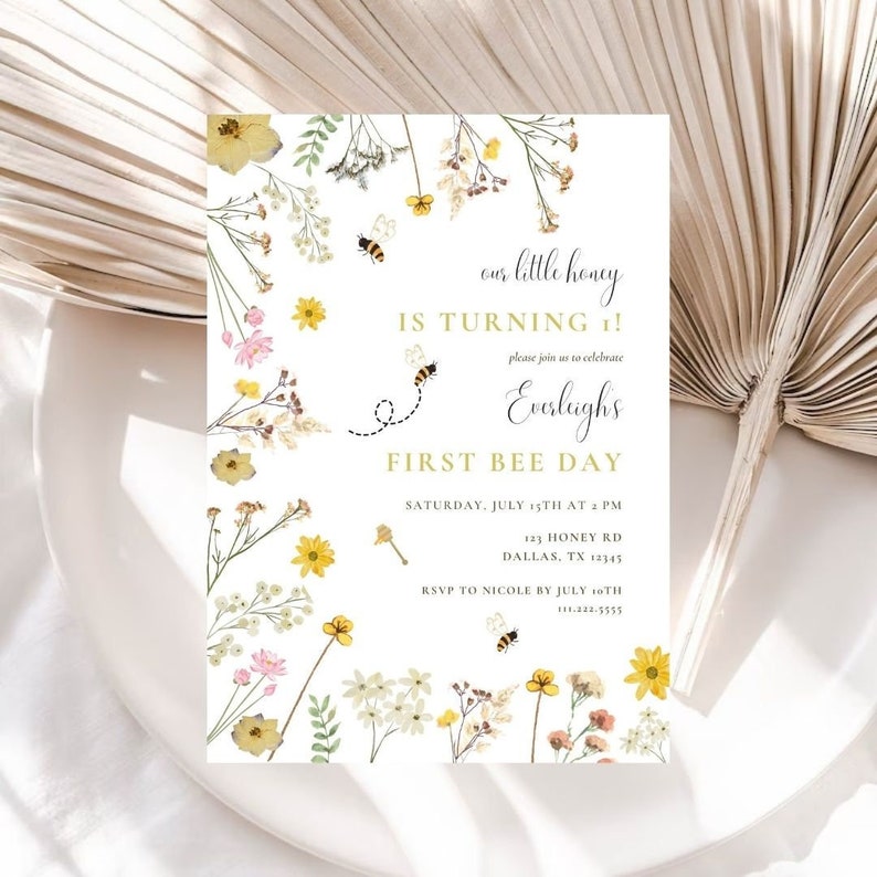 Puede incluir: Una invitaci&oacute;n blanca con un dise&ntilde;o floral con flores amarillas, rosas y blancas. El texto dice "&iexcl;Nuestra peque&ntilde;a miel cumple 1!" y "Primer d&iacute;a de abeja". La invitaci&oacute;n incluye detalles para una fiesta de cumplea&ntilde;os, incluyendo la fecha, la hora, la direcci&oacute;n y la informaci&oacute;n de RSVP.