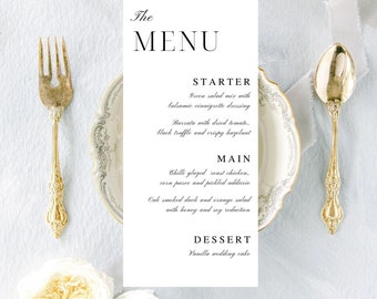 Könnte beinhalten: Eine weiße Hochzeitsmenükarte mit dem Wort "The Menu" oben. Das Menü umfasst eine Vorspeise, ein Hauptgericht und ein Dessert. Die Vorspeise ist ein grüner Salatmix mit Balsamico-Vinaigrette, Burrata mit getrockneter Tomate, schwarzem Trüffel und knusprigen Haselnüssen. Das Hauptgericht ist Chili-glasierter Brathähnchen, Maispüree und eingelegte Adiccio, Eichenholz geräucherte Ente und Orangensalat mit Honig-Soja-Reduktion. Das Dessert ist ein Vanille-Hochzeitstorte.
