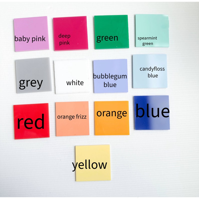 Op de afbeelding: Een verzameling van 12 kleurstalen, elk met een andere kleurnaam erop geschreven. De kleuren omvatten babyroze, dieproze, groen, groene munt, grijs, wit, bubblegum blauw, suikerspin blauw, rood, oranje frizz, oranje en geel.