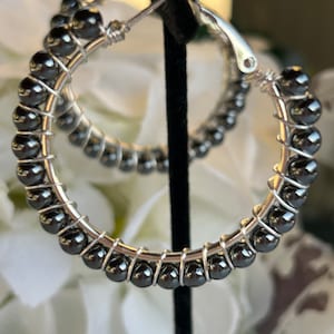 May include: A pair of silver hoop earrings with black beads. The earrings are made of wire and have a simple design.