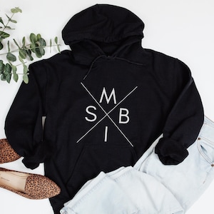 May include: Black hooded sweatshirt with a white graphic design of a cross with the letters "MSBI" inside.