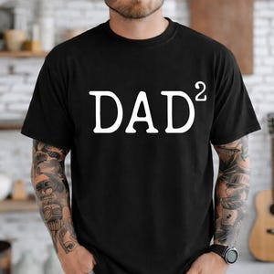 Peut inclure: T-shirt noir à col rond avec le mot "DAD²" imprimé en blanc. Le t-shirt est fait d'une matière douce et a des manches courtes. Le design est simple et audacieux, ce qui en fait un excellent cadeau.