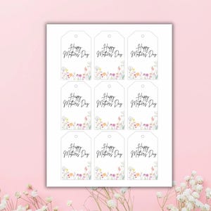 Op de afbeelding: Negen printbare cadeaulabels met een bloemige rand en de tekst "Happy Mother's Day" in zwarte cursieve letters.