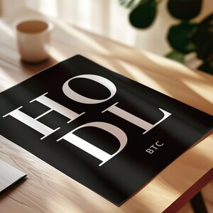 May include: Black and white print with the word "HODL" in large white letters and the abbreviation "BTC" in smaller white letters below. The print is on a black background.