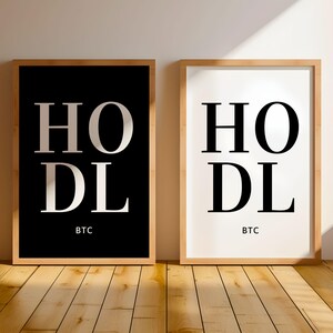 May include: Two framed prints with the word "HODL" in large white letters on a black background and a white background. The word "BTC" is printed below the word "HODL" on both prints.