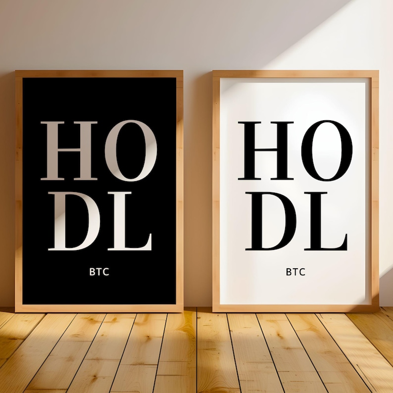 May include: Two framed prints with the word "HODL" in large white letters on a black background and a white background. The word "BTC" is printed below the word "HODL" on both prints.