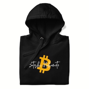 May include: Black hooded sweatshirt featuring a gold Bitcoin symbol and the name "Satoshi Nakamoto" in a white script font. The hoodie has a drawstring and a front pocket.