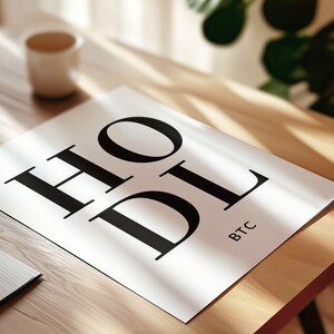 May include: A white poster with the word "HODL" in large black letters. The word "BTC" is written in smaller letters below the word "HODL".