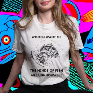 May include: White t-shirt with a black and white graphic of a fish jumping out of the water. The text "Women Want Me" and "The Minds of Fish Are Unknowable" is printed on the shirt.