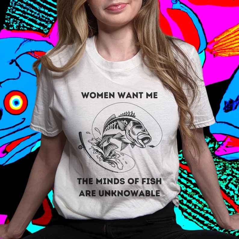 May include: White t-shirt with a black and white graphic of a fish jumping out of the water. The text "Women Want Me" and "The Minds of Fish Are Unknowable" is printed on the shirt.