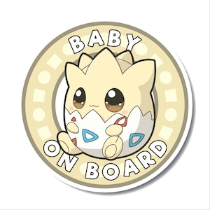 Könnte beinhalten: Ein runder, beiger Aufkleber mit weißem Rand und dem Text "BABY ON BOARD" in braunen Buchstaben. In der Mitte befindet sich ein Cartoon-Bild eines hellgelben Baby-Pokemons mit braunen Augen, das ein weißes Ei mit blauen und roten Markierungen hält.