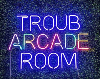 May include: Neon sign with the words "Troub Arcade Room" in rainbow colours against a green background.