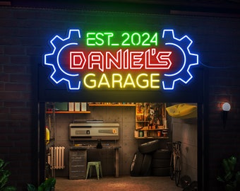 Peut inclure: Un panneau lumineux en néon avec un motif d'engrenage indique "EST. 2024 DANIEL'S GARAGE" en jaune, rouge et vert. Le panneau est au-dessus d'une porte de garage avec un établi et des outils à l'intérieur.
