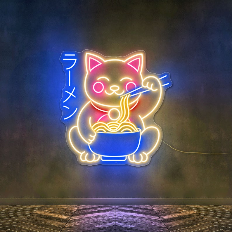 Puede incluir: Letrero de ne&oacute;n de un gato amarillo comiendo fideos ramen de un taz&oacute;n azul. El letrero dice "Ramen" en caracteres japoneses.