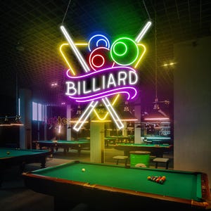 May include: A neon sign with the word "BILLIARD" in a purple and white script. The sign features a yellow triangle with two crossed cues and a cluster of colorful billiard balls.
