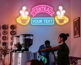 May include: Neon sign with a pink banner that says "CENTRAL" and two yellow coffee cups with steam coming from them. The sign also has a blue banner that says "YOUR TEXT".
