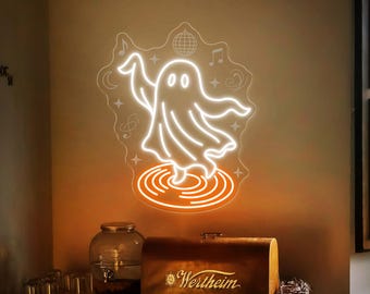 May include: A neon light fixture shaped like a dancing ghost, with musical notes and a disco ball. The light is white and orange, mounted on a beige wall. Below, a wooden box with the word "Wertheim" is visible.