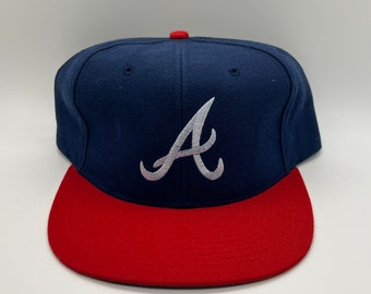 Könnte beinhalten: Eine blaue und rote Baseballkappe mit einem weißen gestickten "A" auf der Vorderseite.