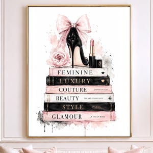 May include: A vertical wall art print featuring a stack of six books with titles Feminine, Luxury, Couture, Beauty, Style, and Glamour. Atop the books sits a black high-heeled shoe with a large pink bow, a pink flower, and a lipstick tube.