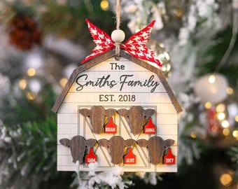 May include: Wooden Christmas ornament shaped like a barn, with the text "The Smiths Family EST. 2018". Features cow head cutouts with name tags. Decorated with a red and white bow.