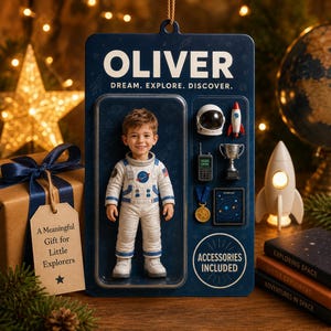 May include: A custom action figure in a dark blue blister pack featuring a child astronaut in a white suit. The packaging displays the name OLIVER, the text DREAM. EXPLORE. DISCOVER., and includes accessories like a helmet, rocket, radio, trophy, medal, and map.