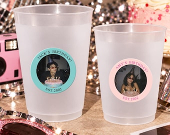 Puede incluir: Dos vasos de plástico esmerilado con etiquetas circulares. El vaso grande tiene un borde turquesa con el texto "JACK'S BIRTHDAY! EST. 2002" y una foto. El vaso pequeño tiene un borde rosa con "AMY'S BIRTHDAY! EST. 2002" y una foto de una persona.