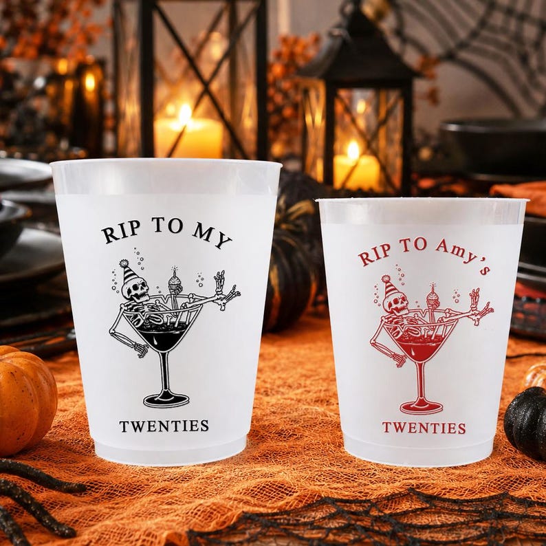 May include: Two frosted plastic cups featuring a graphic of a skeleton in a martini glass wearing a party hat. The left cup has black text reading RIP TO MY TWENTIES, and the right cup has red text reading RIP TO Amy's TWENTIES.