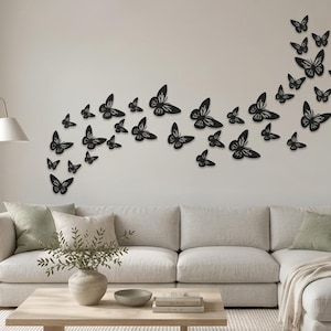 May include: A collection of black butterfly wall decals arranged in a sweeping, upward-curving formation. The set consists of numerous individual butterfly silhouettes of varying sizes, each featuring intricate cut-out wing patterns.