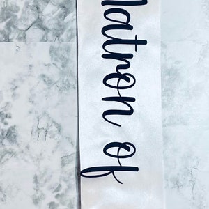 Puede incluir: Sash de sat&eacute;n blanco con texto negro que dice "Reina de las tinas" y un gr&aacute;fico de corona negra.