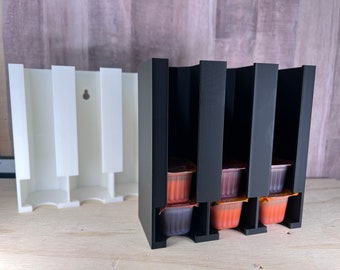 Peut inclure: Un distributeur mural noir et blanc pour sachets de condiments en portions individuelles. Le distributeur a six fentes et contient des sachets orange.