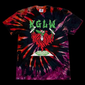 May include: A short-sleeve tie-dye t-shirt in black, red, and purple with a graphic print. The design features the green text KGLW above a green crocodile with spiral eyes, a small white rabbit, and a geometric green pyramid shape at the base.