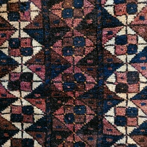 Puede incluir: Un primer plano de una alfombra colorida con un patrón geométrico. La alfombra está hecha de tejido tejido y tiene una variedad de colores, incluyendo rojo, azul, blanco y negro.