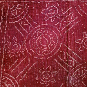 May include: A red fabric with a white pattern of small circles and dots. The fabric is quilted with a white thread.