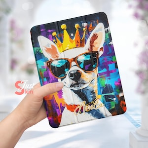 May include: A colorful tablet case with a cartoon image of a chihuahua wearing sunglasses and a gold crown. The case has a white background with splashes of color and the name "Amelia" written in gold lettering.