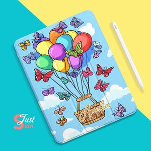 Puede incluir: Una funda para iPad azul con un diseño de globo aerostático colorido. Los globos están llenos de mariposas de colores y el nombre Amelia está escrito en letras doradas en la funda.