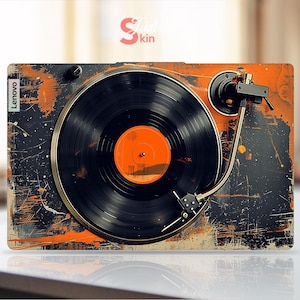 May include: A vintage-style laptop skin with a black and orange design featuring a record player with a vinyl record. The skin has the word "Lenovo" printed on the left side.