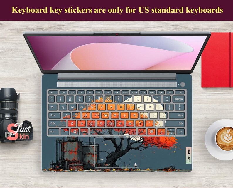 May include: Laptop with a custom keyboard skin featuring an industrial scene with a tree and orange leaves. The keyboard keys have a colorful, distressed design. The laptop is open, displaying a pink and white screen. Text at the top reads: "Keyboard key stickers are only for US standard keyboards."