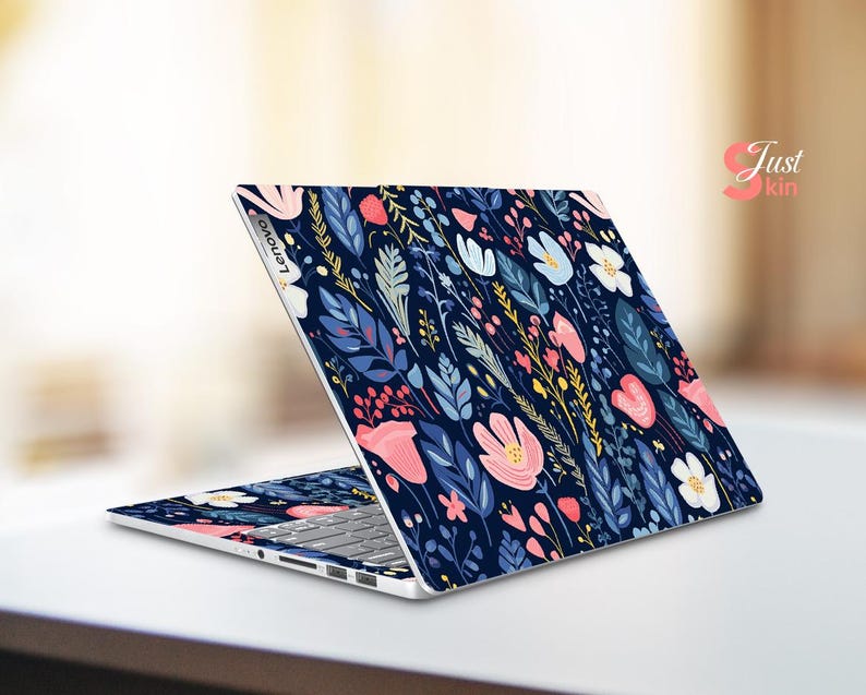 Op de afbeelding: Een Lenovo laptop met een bloemen skin. De skin heeft een donkerblauwe achtergrond met een patroon van roze, witte en gele bloemen, samen met blauwe en groene bladeren. De laptop is open op een wit oppervlak.
