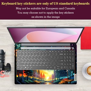 K&ouml;nnte beinhalten: Ein Laptop mit einem bunten Aufkleber mit einer Waldszene auf der Tastatur. Der Aufkleber zeigt einen Sonnenuntergang und B&auml;ume. Der Laptop ist ge&ouml;ffnet und der Bildschirm zeigt einen rosa und wei&szlig;en Hintergrund. Der Text "Lenovo" ist in der unteren rechten Ecke des Laptops sichtbar.