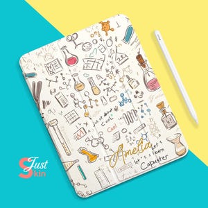 Könnte beinhalten: Eine weiße iPad-Hülle mit einem bunten Kritzel-Design mit Kolben, Reagenzgläsern und anderen wissenschaftlichen Motiven. Der Text "Amelia let's learn Capuster" ist in goldener Kursivschrift auf der Hülle geschrieben.
