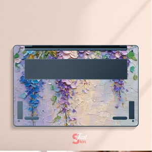 K&ouml;nnte beinhalten: Laptop-Skin mit einem strukturierten Blumendesign in Lila, Blau und Gr&uuml;n. Das Kunstwerk &auml;hnelt einem impressionistischen Gem&auml;lde mit sichtbaren Pinselstrichen. Die Haut hat einen dunkelgrauen L&uuml;ftungsbereich und den Text "Just kin".