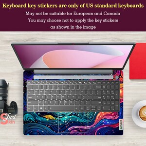 Puede incluir: Un port&aacute;til con una funda de teclado vibrante que muestra un dise&ntilde;o abstracto en tonos azules, morados y naranjas. El teclado est&aacute; a la vista y la pantalla del port&aacute;til muestra una imagen rosa claro y blanca. El texto indica que las pegatinas del teclado son solo para teclados estadounidenses.