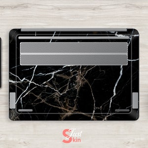 Puede incluir: Piel para port&aacute;til negra con un patr&oacute;n de m&aacute;rmol blanco. La piel tiene una rejilla de ventilaci&oacute;n plateada.