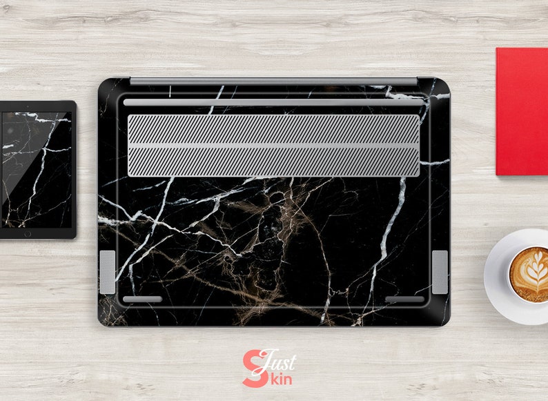 Puede incluir: Piel para port&aacute;til negra con un patr&oacute;n de m&aacute;rmol blanco. La piel tiene una rejilla de ventilaci&oacute;n plateada.