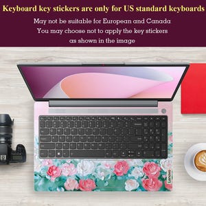 Peut inclure: Un ordinateur portable avec un autocollant de clavier floral. L'autocollant pr&eacute;sente des roses roses, blanches et vertes sur un fond vert. L'ordinateur portable est ouvert et l'&eacute;cran affiche un motif abstrait rose et blanc. Le texte sur l'autocollant indique "Keyboard key stickers are only for US standard keyboards. May not be suitable for European and Canada. You may choose not to apply the key stickers as shown in the image."