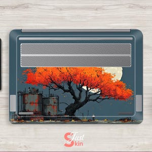 May include: Laptop skin featuring an artistic illustration of a tree with vibrant orange leaves against a full moon. The design includes industrial structures and a figure, set against a dark blue backdrop. The skin is on a laptop, with a tablet and coffee cup nearby.