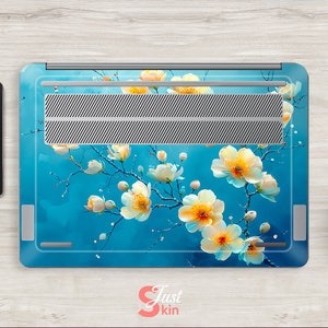 May include: A laptop skin with a floral design. The design features white flowers with yellow centers on a blue background. The laptop skin is made of a durable material and is easy to apply.