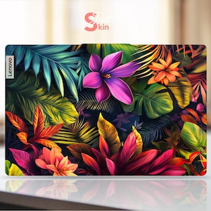 May include: A Lenovo laptop skin featuring a vibrant floral and foliage design. The skin showcases a variety of colorful tropical plants, including large purple flowers, orange blossoms, and lush green leaves. The design is set against a dark background.