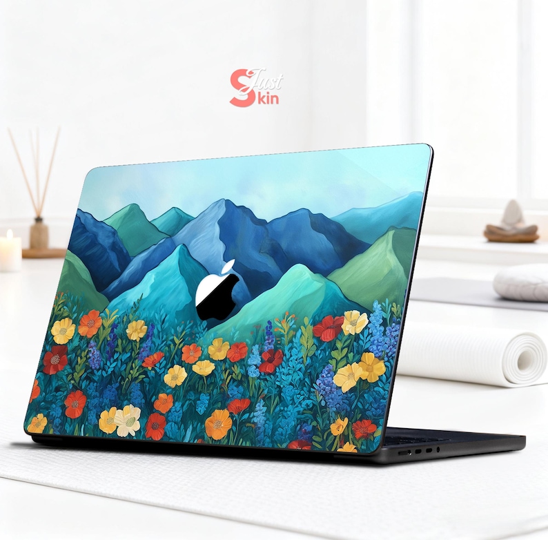 Pode incluir: Um laptop com um design de montanha e floral. O design apresenta montanhas azuis e verdes, um c&eacute;u azul e um campo de flores coloridas em tons de vermelho, amarelo e laranja. O laptop tem uma base preta e o logotipo da Apple &eacute; vis&iacute;vel.