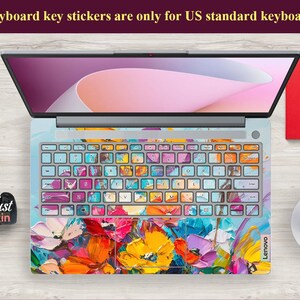 Puede incluir: Un teclado de port&aacute;til con pegatinas de teclas abstractas florales de colores. El teclado es gris y tiene el logotipo de Lenovo. El port&aacute;til est&aacute; abierto y la pantalla muestra un fondo rosa y blanco.